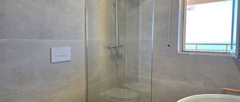 Une salle de bain avec une douche à parois de verre, des toilettes et un grand lavabo.