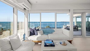 Una sala de estar moderna con un sofá blanco, una mesa de centro y vistas al mar.
