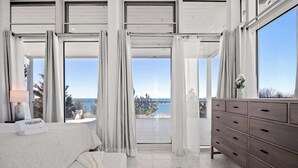 Un dormitorio con cama, cómoda y vista al mar.
