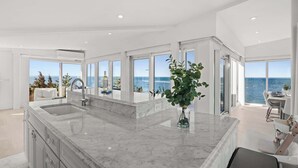 Una cocina moderna con una isla grande de mármol, un lavamanos y vistas al mar.