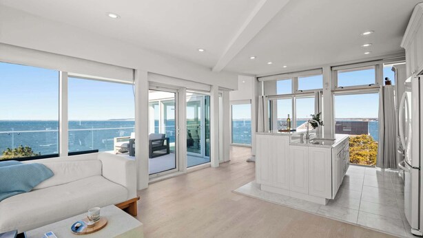 Un interior moderno con balcón, una zona de cocina y un área de descanso con vistas al mar.
