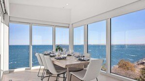 Un comedor con una mesa grande, sillas y vistas al mar.