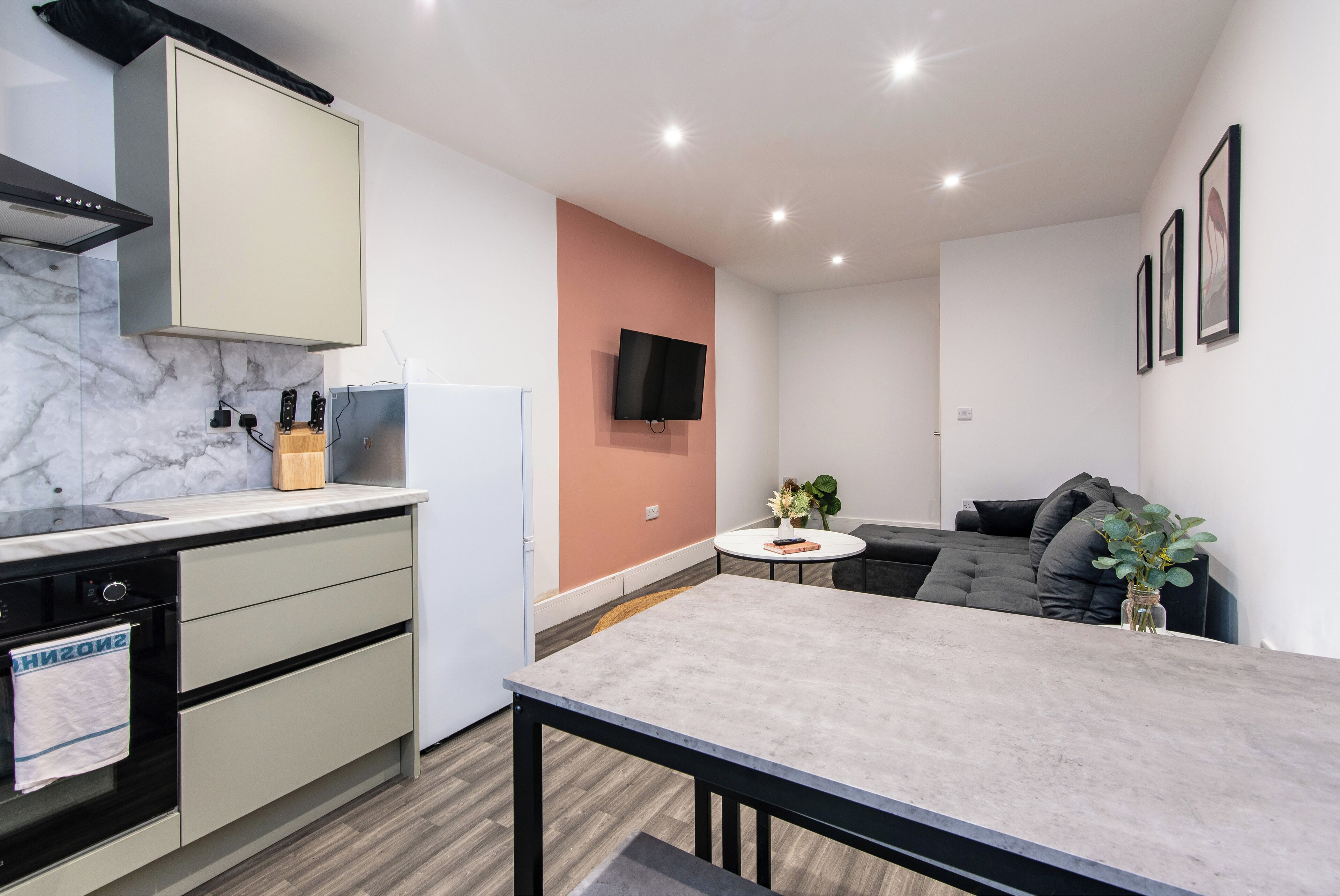 A modern kitchen with a marble countertop, built-in oven, and a dining area with a table and chairs.