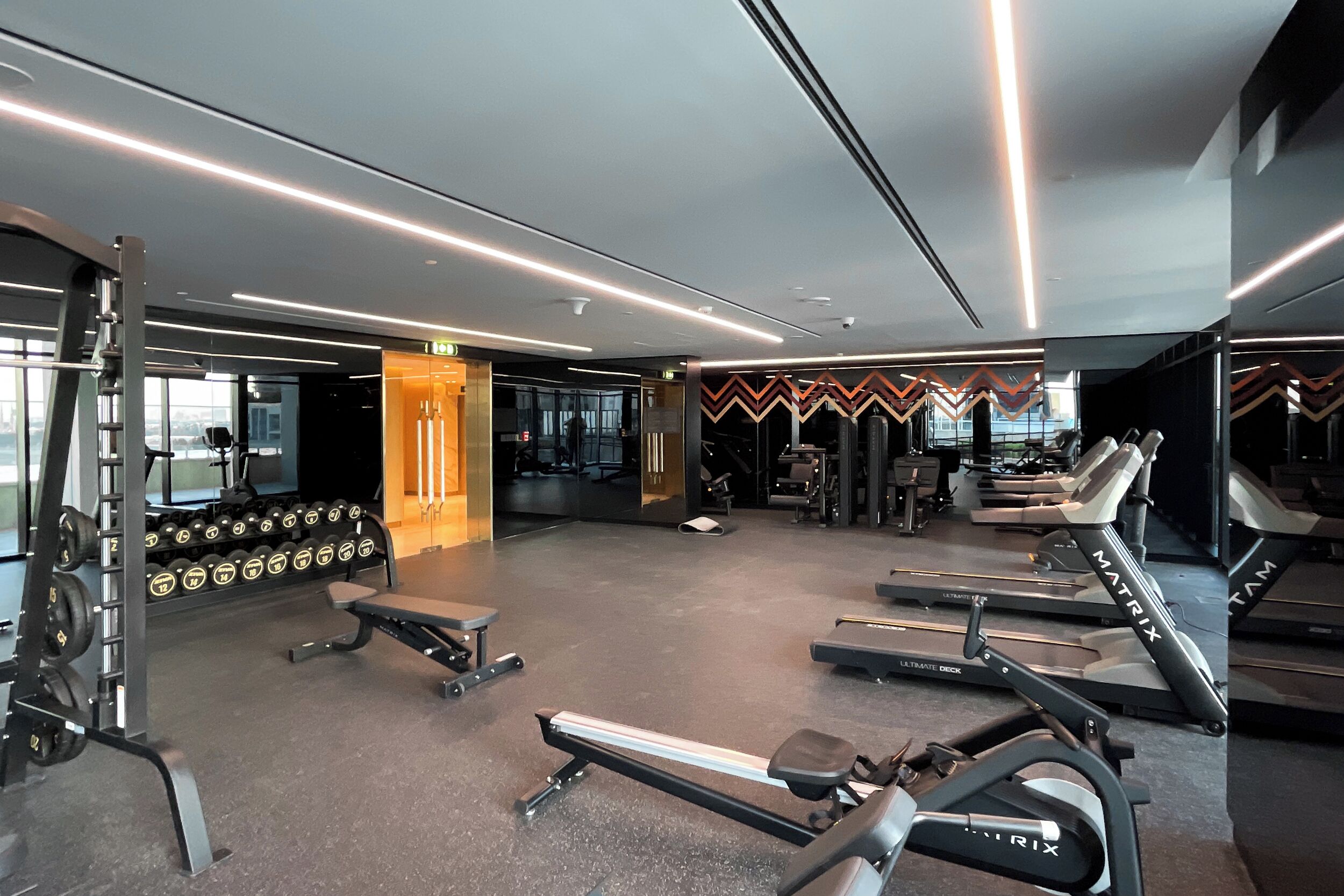 Een fitnessruimte met loopbanden, krachtapparaten en gewichten.