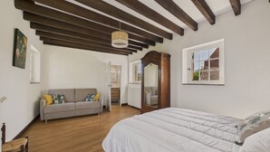 A bedroom with a large bed, a wooden ceiling, a window, and a door leading to a bathroom. - Lovely house with jacuzzi for 8 people (Mauzens-et-Miremont)