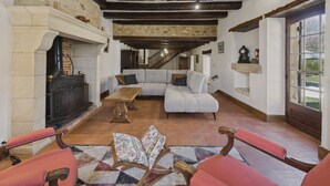 A cozy living room with a fireplace, a sofa, and a wooden table. - Lovely house with jacuzzi for 8 people (Mauzens-et-Miremont)