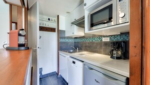 Una cocina compacta equipada con microondas, cafetera y lavavajillas.