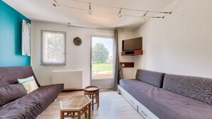 Una sala de estar con un sofá, una mesita de madera y un televisor montado en la pared.