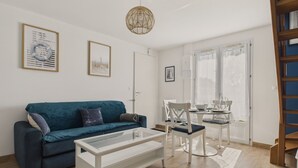 A modern living room with a teal sofa, a white coffee table, and a dining area with a white table and chairs. - House for 4 with garden, 500m from the beach (Piriac-sur-Mer)
