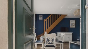 A dining area with a wooden staircase, white furniture, and a blue wall. - House for 4 with garden, 500m from the beach (Piriac-sur-Mer)