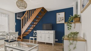 A modern living room with a wooden staircase, white furniture, and a television on a cabinet. - House for 4 with garden, 500m from the beach (Piriac-sur-Mer)