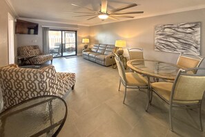 A spacious living area with a sofa, armchair, and dining table with chairs. - Vacation At Bac Bay! Fun In The Sun! 2B/2B Condo Walk To Beach! (Fort Myers Beach)