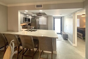 A modern kitchen with a central island, bar stools, and a dining area with a bench.