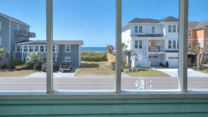 Eine Wohnstraße mit Häusern, blauem Himmel und Blick auf das Meer.