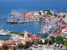 A marina with numerous boats docked, surrounded by buildings with red roofs.