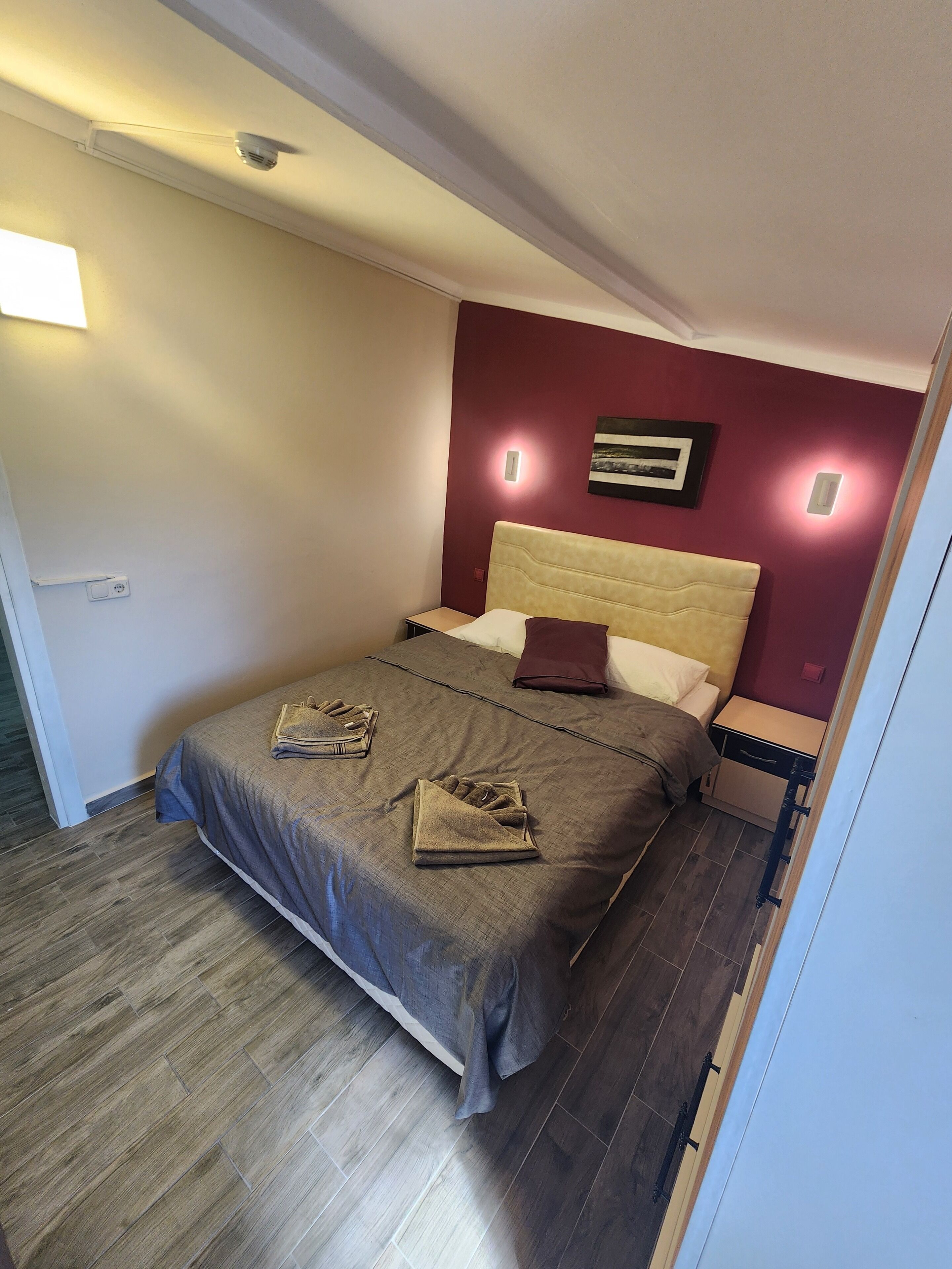Un dormitorio con cama, mesita de noche y lámpara de pared.