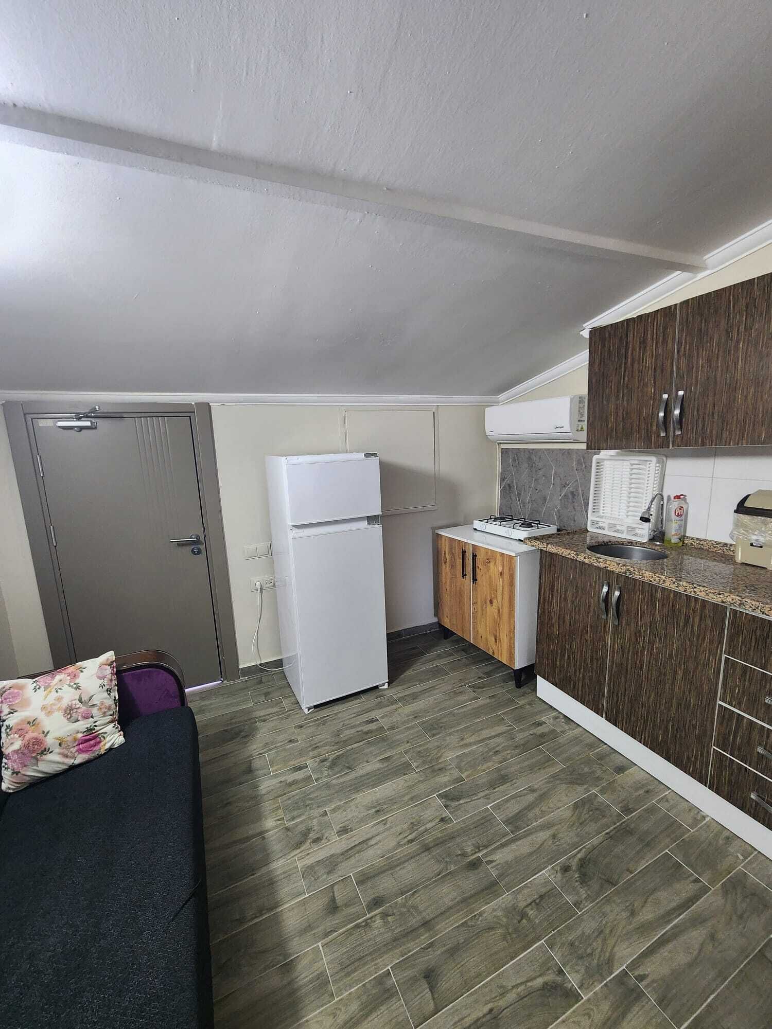 Eine kleine Küche mit Kühlschrank, Herd und Holzschränken.