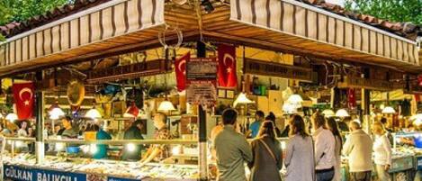 A bustling outdoor market with various stalls and people shopping.