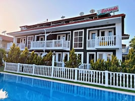 A two-story building with balconies, a swimming pool, and a sign for "Schrade Apartment Hotel".