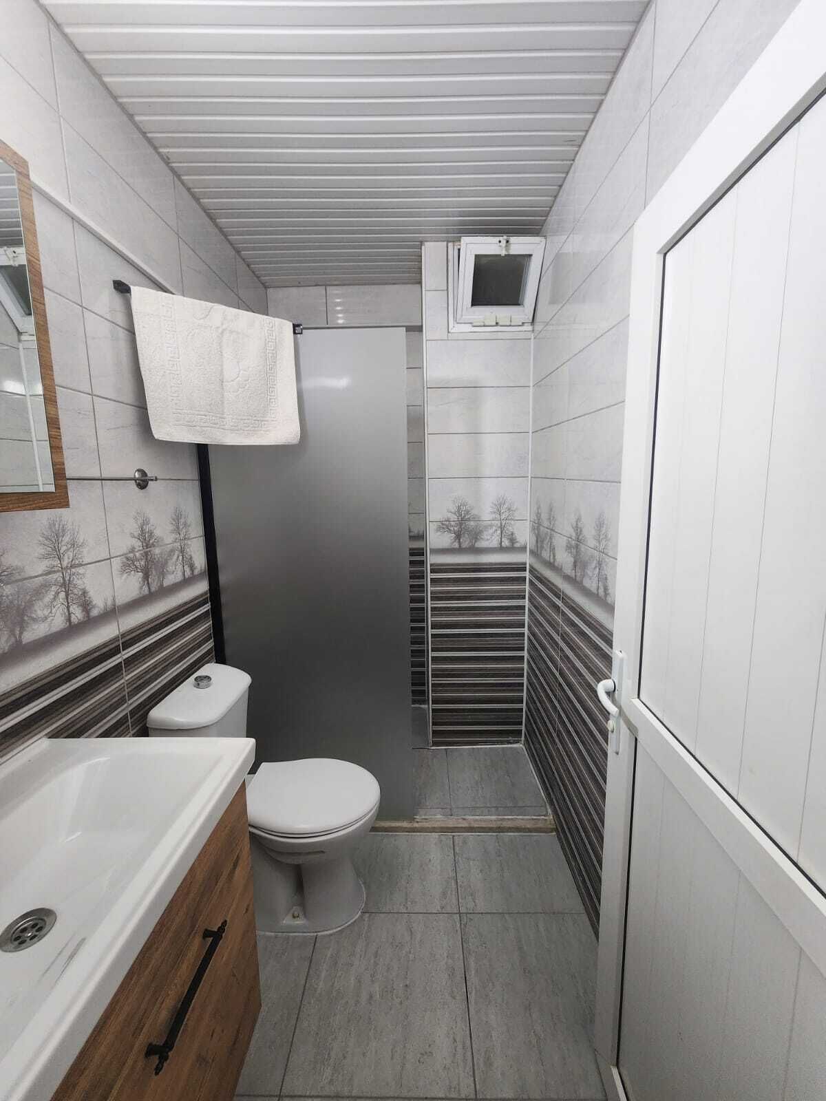 A compact bathroom with a toilet, sink, and shower.