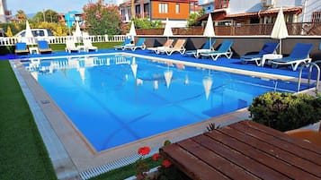A swimming pool with lounge chairs and a wooden deck.