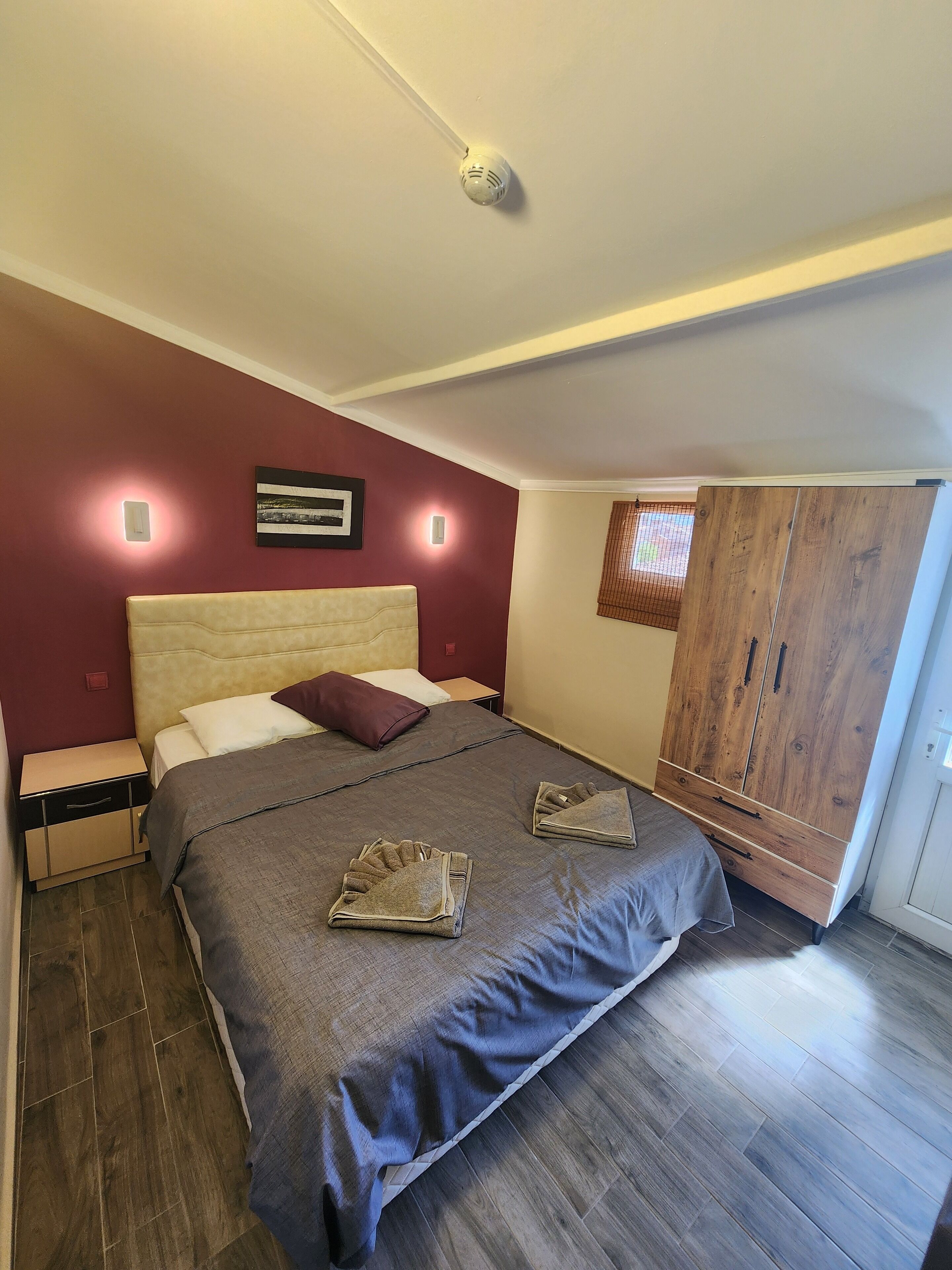 A bedroom with a bed, nightstands, a wardrobe, and a window.