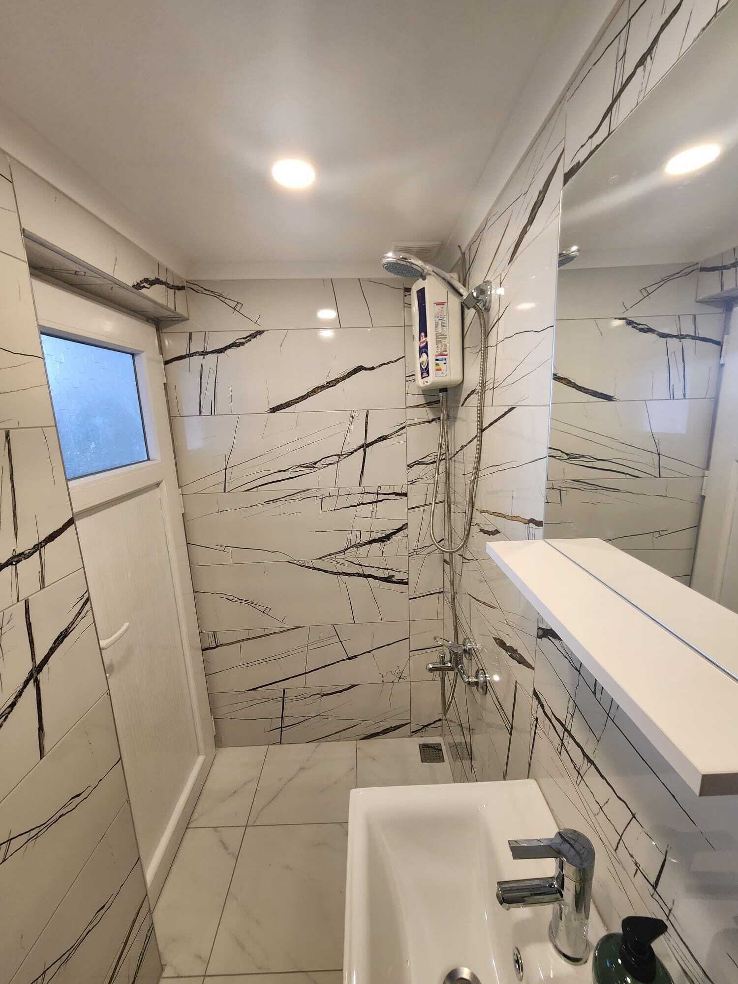 A modern bathroom with a shower, a sink, and a window.