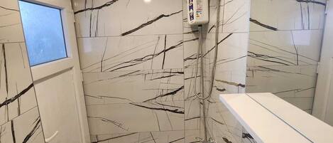 A modern bathroom with a shower, a sink, and a window.