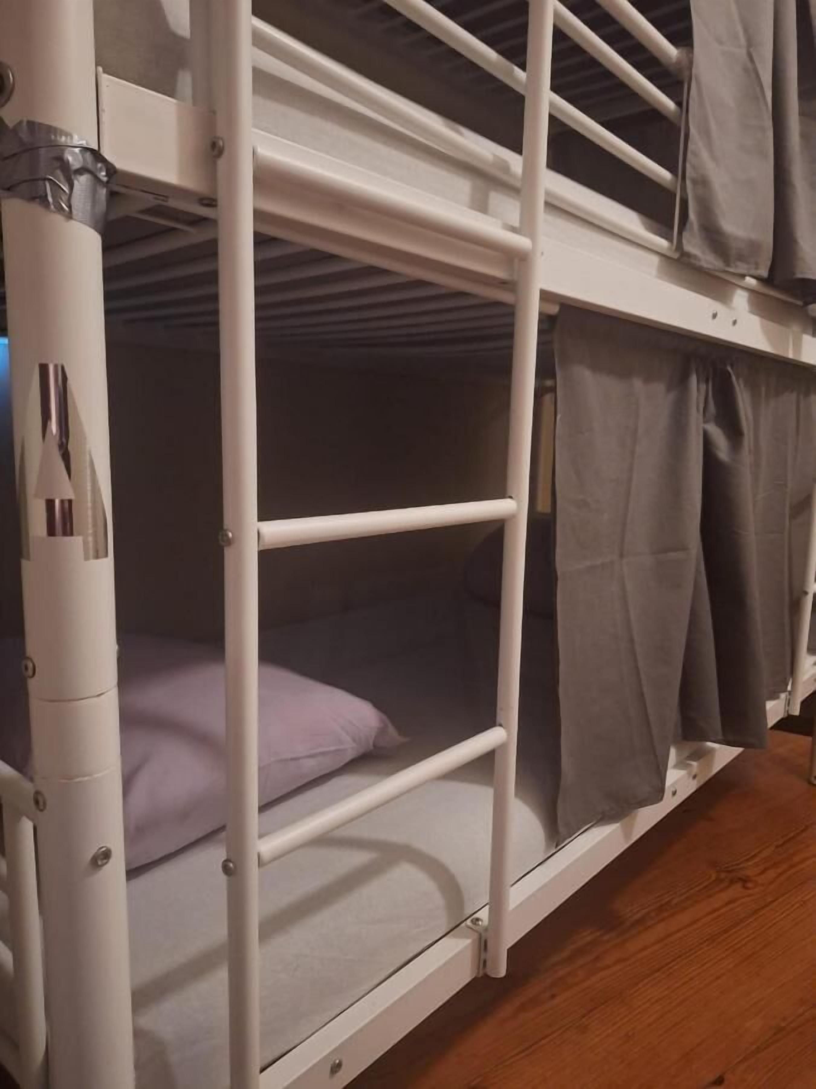Una cama litera con escritorio extraíble y cortina.