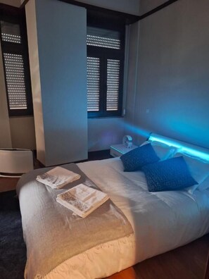 Een moderne slaapkamer met een bed, nachtkastje en raam met zonwering.