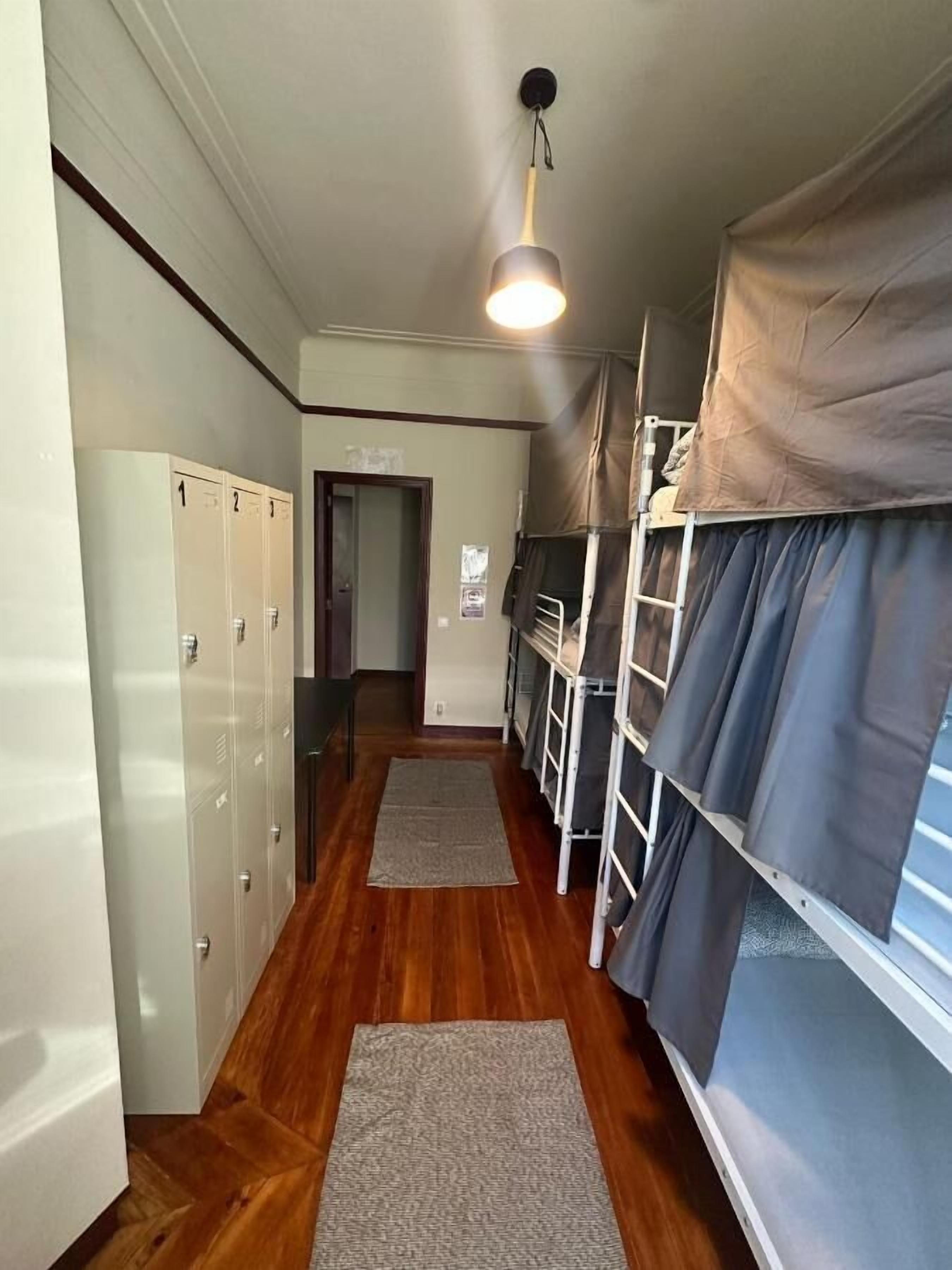 A corridor with bunk beds, lockers, and a hanging light fixture.