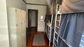 A corridor with bunk beds, lockers, and a hanging light fixture.