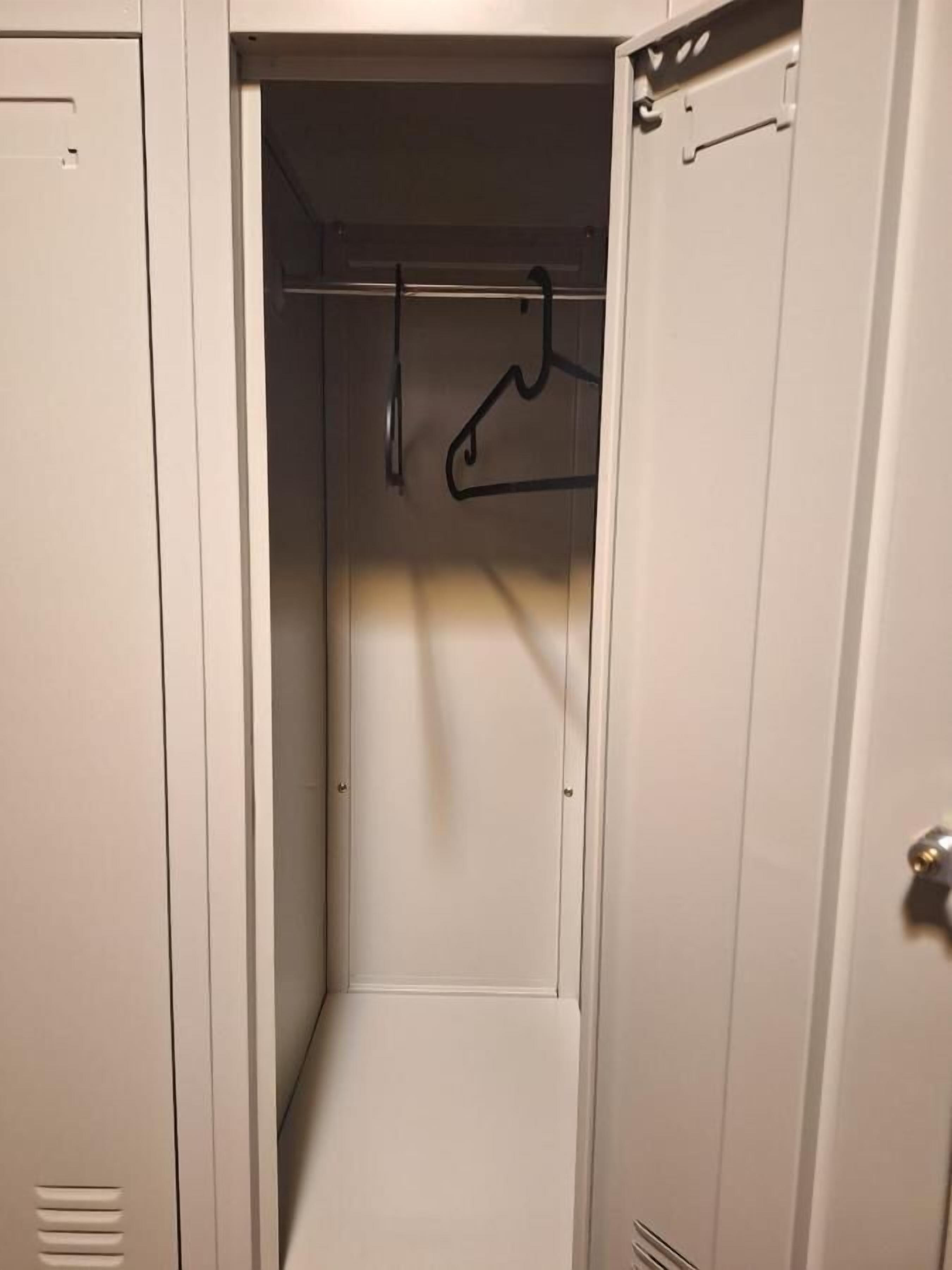 A narrow walk-in closet with a single clothing rack.