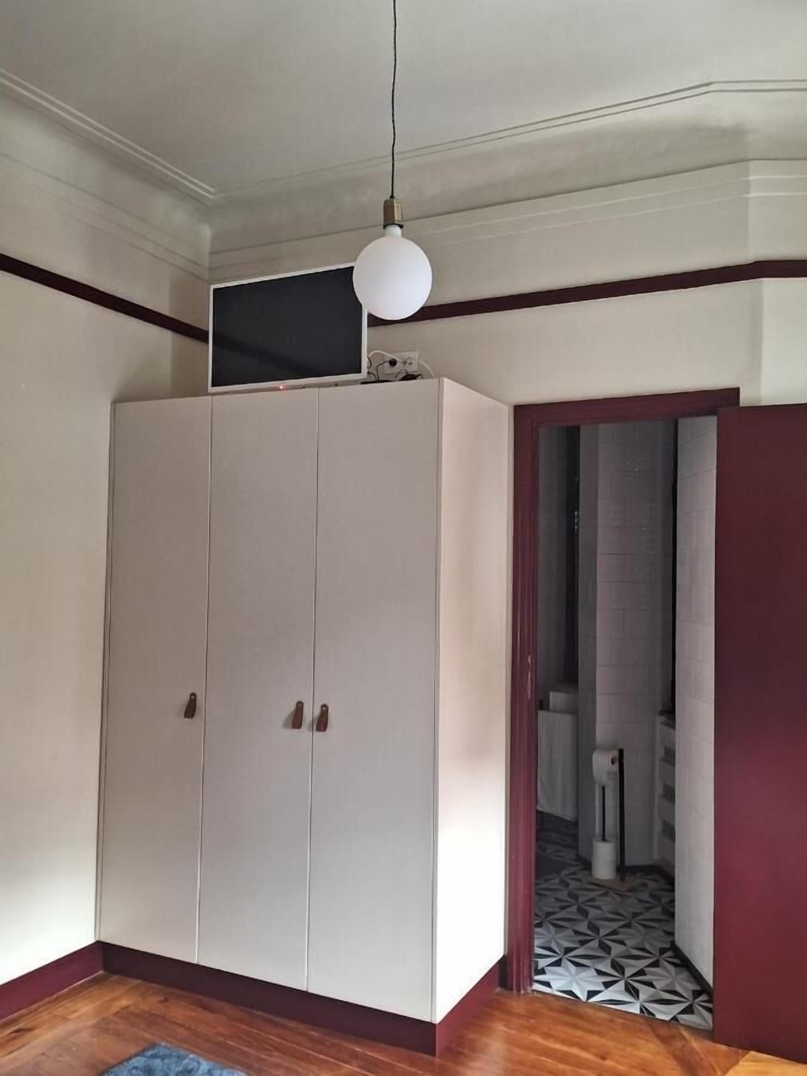 Une pièce avec une grande armoire, un téléviseur posé sur le dessus, et un sol à motifs.