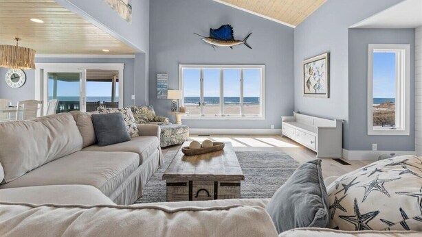 A spacious living room with a large window, a wooden ceiling, and a decorative fish hanging on the wall. - Grand View, Ocean Isle Beach (Ocean Isle Beach)