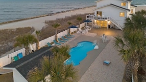 A beachfront property with a swimming pool, lounge chairs, and a staircase leading to a balcony. - Grand View, Ocean Isle Beach (Ocean Isle Beach)