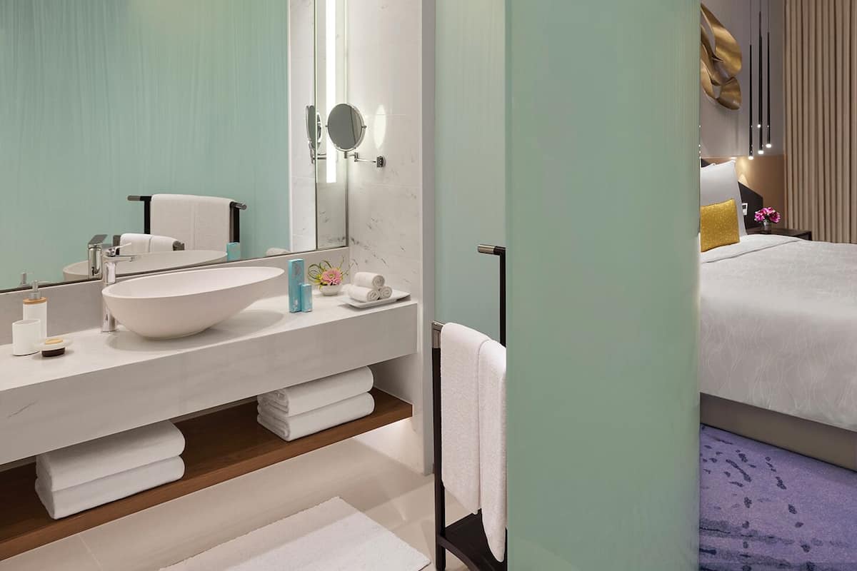 A modern bathroom with a large mirror, a freestanding sink, and a towel rack.
