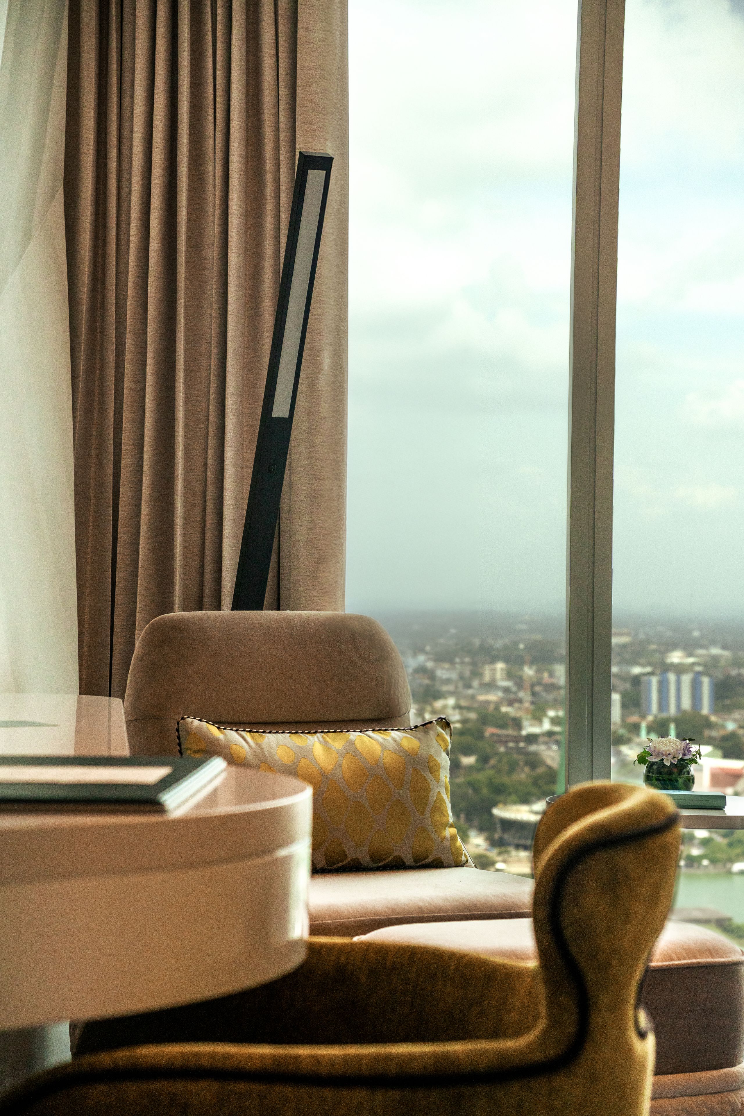 Habitación con vistas a un paisaje urbano a través de un ventanal grande, un sofá, una mesa y una silla.