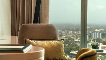 Habitación con vistas a un paisaje urbano a través de un ventanal grande, un sofá, una mesa y una silla.