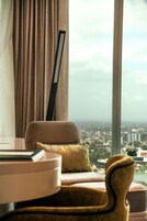 Habitación con vistas a un paisaje urbano a través de un ventanal grande, un sofá, una mesa y una silla.