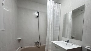 Ein Badezimmer mit einer Badewanne, einer Dusche, einem Waschbecken und einem Spiegel.