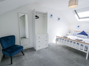 A bedroom with a bed, a chair, a wardrobe, and a mirror. - The Coach House (Dolgellau)