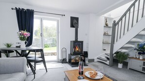 A modern living room with a sofa, a dining table with plates and glasses, a fireplace, and a staircase.