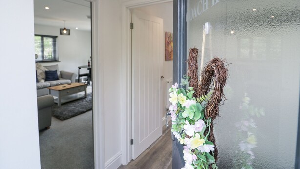 A modern interior with a glass door labeled "THE HOUSE" and a living area with a sofa and coffee table.