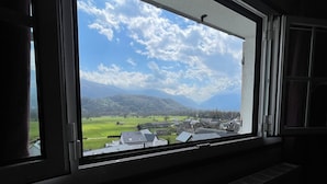 Ein Fenster mit Blick auf eine grüne Landschaft und Gebäude.