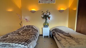 Ein Hotelzimmer mit zwei Betten, einem Nachttisch mit Blumenvase und Wandlampen.