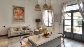 Ein modernes Wohnzimmer mit einer Couch, einem Essbereich mit Tisch und Stühlen sowie einem großen Fenster mit Vorhängen.