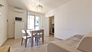 A compact living space with a dining area, kitchenette, and a sofa.
