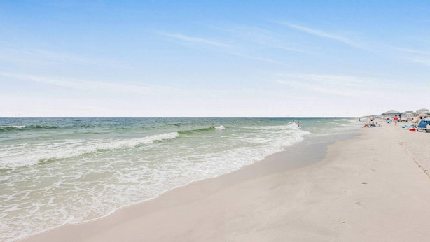 A beach with waves and a clear sky.