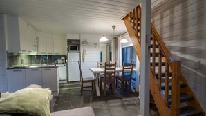 A compact kitchen with white cabinets, a microwave, and a dining area with a table and chairs.